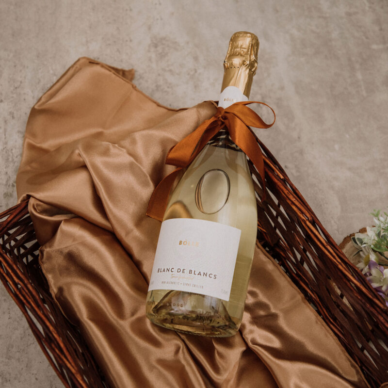Flaska af BOLLE Blanc de Blancs í tágakörfu á gylltu satíni