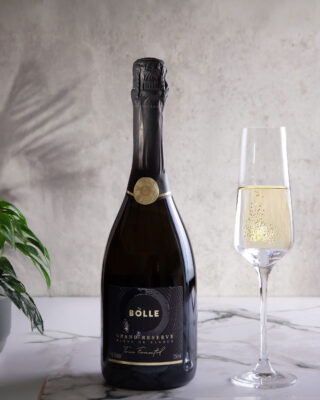 Svört flaska af BOLLE Grand Reserve og freyðivín í háu glasi á hvítum marmara
