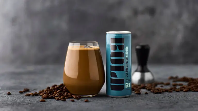 Dós af BOLD Protein Iced Espresso og glas með ísköldu kaffi á dökkum steini