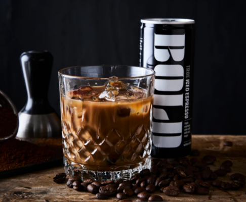 Dós af BOLD True Iced Espresso og ískaffi með klökum í kristalsglasi innan um kaffibaunir