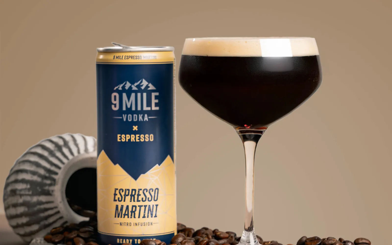 Dós af 9 MILE Espresso Martini og glas með froðu innan um kaffibaunir